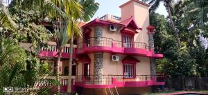a pink building with a balcony on the side of it at Paradise Castle Villa in Auroville