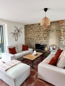 a living room with couches and a stone wall at Maison cosy proche Cancale et Mont-Saint-Michel in Saint-Méloir-des-Ondes