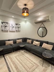 a living room with a black couch and a mirror at Beautiful apartment overlooking King Road in Jeddah