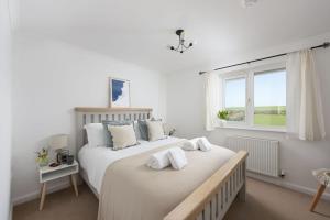 two beds in a white bedroom with a window at Poldreth - situated above the golden sand and rolling waves of Porthtowan Beach in Porthtowan