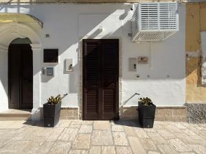 a white building with a door and two potted plants at La Casupola by MONHOLIDAY in Monopoli