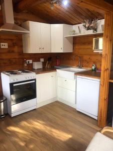 a kitchen with white cabinets and a stove at Misty Mountain Log Cabin - Trawsfynydd in Trawsfynydd