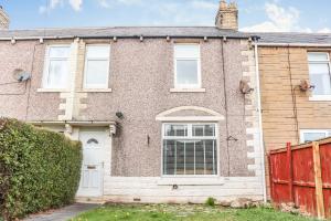 une maison en briques avec une clôture rouge devant elle dans l'établissement 3 BDR Entire Home Sleeps Up to 5 Contractors & Families Long or Short Stay Free WiFi & Parking, à Lynemouth