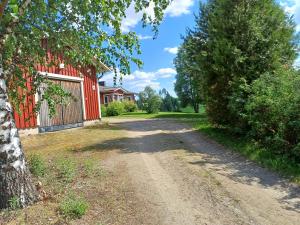 a dirt road next to a red house with a tree at Naurismäki Iisalmi in Runni