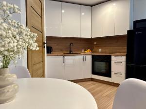 una cocina con armarios blancos y una mesa con un jarrón de flores en Zinc FAM, en Oświęcim 12 fotos más