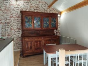 a dining room with a wooden cabinet and a table at La grange du Lucimond in Saint-André