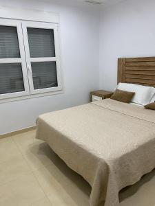 a bedroom with a large bed and two windows at Villa Loma Beach in Chiclana de la Frontera
