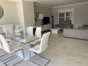a living room with a glass table and white chairs at Villa Loma Beach in Chiclana de la Frontera