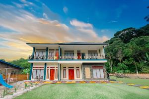 a white house with red doors and a yard at Simangande View & Resto by Staigo in Ambarita
