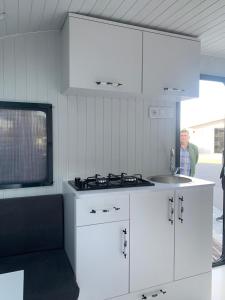 a man in a kitchen with white cabinets and a sink at Caravan suit in Bitlis