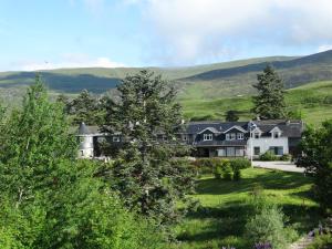 ein Haus in den Hügeln mit einem grünen Feld in der Unterkunft Laggan Hotel in Laggan