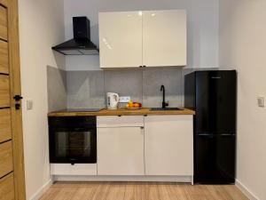 a kitchen with white cabinets and a black refrigerator at Cozy Cottage in Oświęcim +12 photos