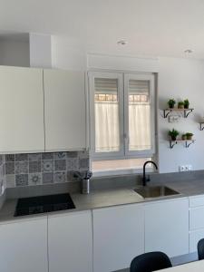 a kitchen with white cabinets and a sink and two windows at El salon de los abuelos in Trescasas +20 photos