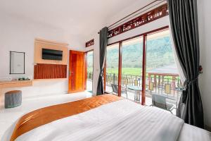 a bedroom with a bed and a large window at Simangande View & Resto by Staigo in Ambarita