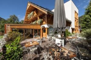 an outdoor patio with tables and chairs and an umbrella at Hotel Lipa in Kranjska Gora