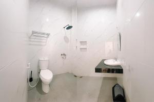a white bathroom with a toilet and a sink at Simangande View & Resto by Staigo in Ambarita