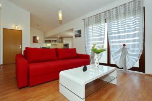 a living room with a red couch and a white table at Apartments Maslina Božava in Božava