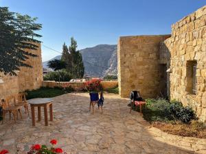 a stone patio with chairs and a table and flowers at Dana Tourist Hotel in Dana