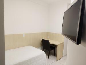 a room with a bed and a desk with a television at Hotel e Restaurante La Carreta in Tangara da Serra