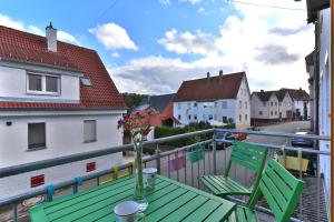a balcony with a green table and chairs and houses at Nürtingen 90 qm lichtdurchflutete Wohnung im Loft-Style mit Balkon und Nähe zum Neckar in Nürtingen