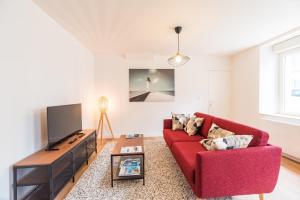 ein Wohnzimmer mit einem roten Sofa und einem Fernseher in der Unterkunft Charmante Maison Bretonne au Cœur de l'Île Grande in Pleumeur-Bodou