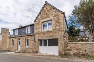 ein altes Steinhaus mit einer weißen Garage in der Unterkunft Charmante Maison Bretonne au Cœur de l'Île Grande in Pleumeur-Bodou