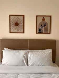 deux images encadrées sur le mur au-dessus d'un lit dans l'établissement Privado by Manazil, 12 First Guest! Stylish Lakeview 2BR, au Caire