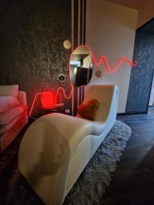 un salon avec un canapé blanc et une chaise rouge dans l'établissement La Maison Parfum d'Amour, à Le Landreau