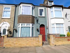una casa con una puerta roja y una valla de ladrillo en 4 Trafalgar Square - 3 Bed House - Great Yarmouth, en Great Yarmouth
