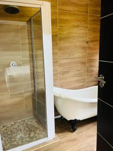 a bathroom with a tub and a glass shower at Laicah House in Tlokweng +28 photos