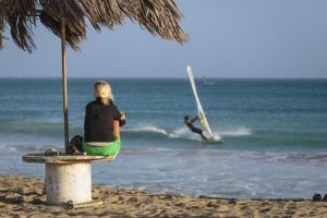a woman sitting on a bench on the beach at Azalea Capo Verde Laura in Santa Maria