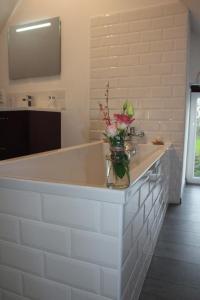 a white bathroom with a tub with a vase of flowers on it at La Catiniere in Arnage +23 photos