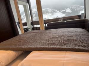 a bed in a room with a large window at Malejo - HochkönigCard - Pool - Ski-in & Ski-out in Maria Alm am Steinernen Meer +41 photos