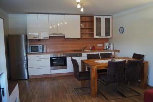 una cocina con mesa de madera y una cocina con armarios blancos. en Appartement Felix en Kaprun