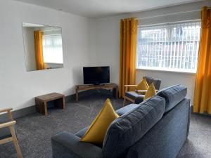 a living room with a couch and a tv at The Bawdens Holiday Apartments in Blackpool