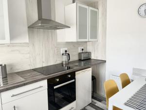 a kitchen with white cabinets and a stove top oven at The Bawdens Holiday Apartments in Blackpool