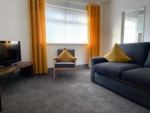 a living room with a couch and a television at The Bawdens Holiday Apartments in Blackpool