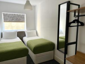 a small room with two beds and a mirror at The Bawdens Holiday Apartments in Blackpool