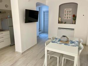 a kitchen and dining room with a white table and chairs at Casa Manila Isola d'Elba in Portoferraio