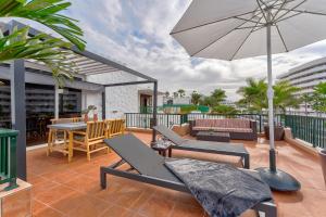 a patio with chairs and an umbrella and a table at Luxury & Panorama Apartment in Costa de Adeje