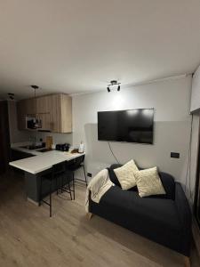a living room with a black couch and a kitchen at Agradable loft en Pucón in Pucón