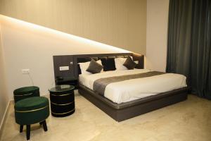 a bedroom with a large bed with two green stools at The Carnation Mound in Haldwāni