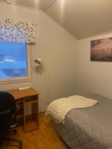 Un dormitorio con una cama y un escritorio y una ventana. en Sweet home- room upstairs near skicenter Ounasvaara and golf course, en Rovaniemi 4 fotos más