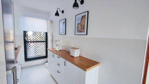コミージャスにあるBonito dúplex con vistas al marの白いキャビネットと木製カウンター付きのキッチン +25枚の写真