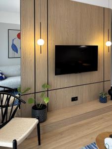 オルシュティンにあるApartament Premium nad jeziorem, przy samej plaży miejskiejの木製の壁にテレビ付きのリビングルーム