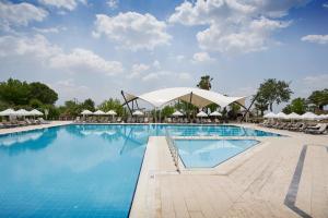 una piscina en un complejo con sillas y sombrillas en Richmond Pamukkale Thermal, en Pamukkale