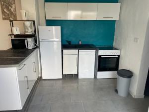 a kitchen with white appliances and a blue wall at Les embruns IV in Saint-Jean-de-Monts