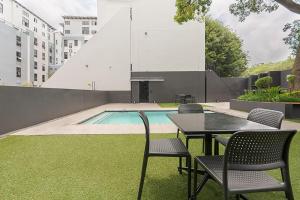 a table and chairs next to a swimming pool at The Bolton serviced apartments Rosebank in Johannesburg