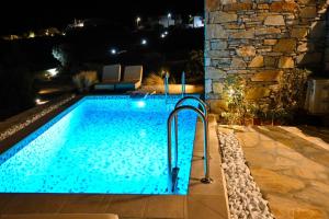 a swimming pool with blue water at night at Schinoza luxury suites in Skhoinoussa +15 photos