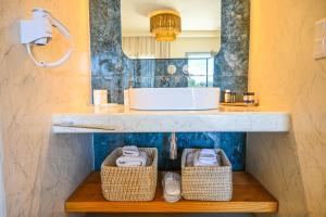 a bathroom with a sink and baskets on a shelf at Schinoza luxury suites in Skhoinoussa